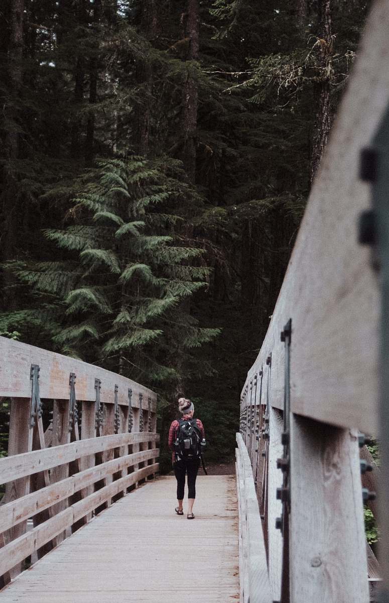 united states woman walking on brown wooden bridge path